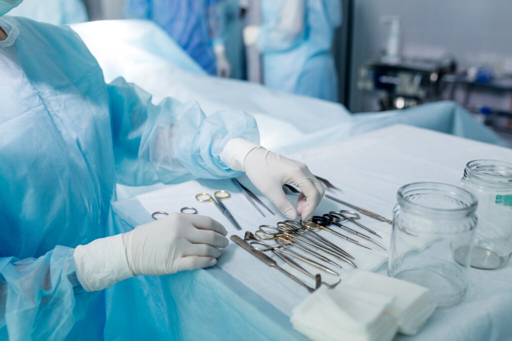 nurse in sterile gloves choosing tool to perform surgery